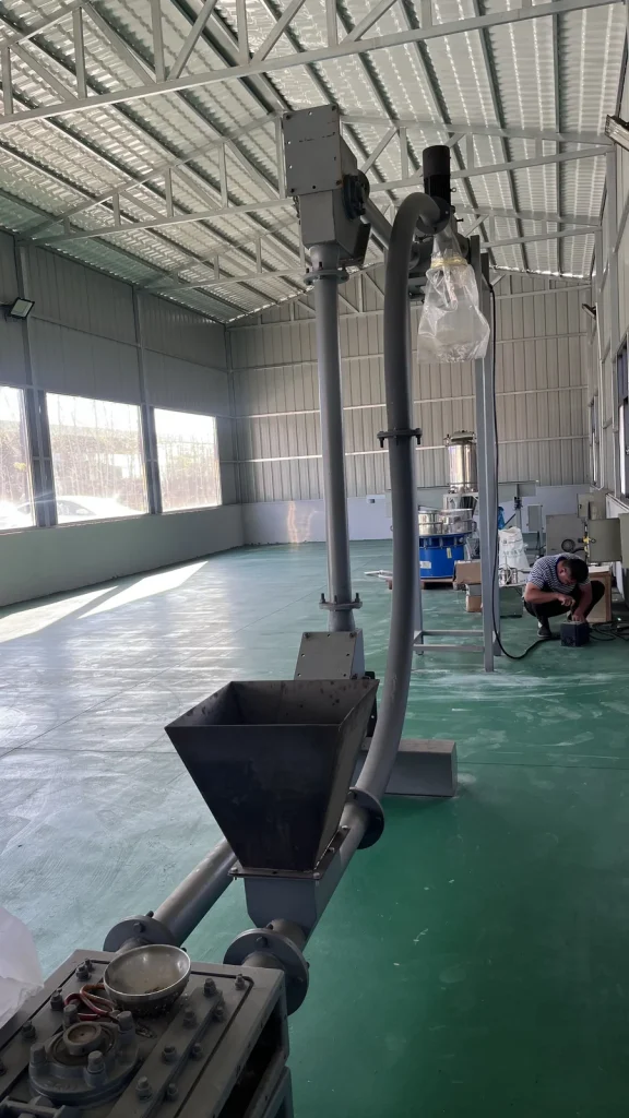 Vertical pipe chain conveyor with a feed hopper and rising tube
